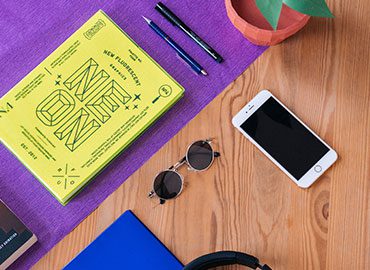 A table with headphones, sunglasses and an iphone.