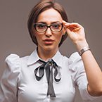 A woman wearing glasses and holding her hand up to the side of her head.