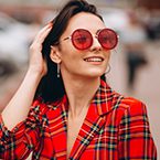 A woman in red jacket and sunglasses smiling.