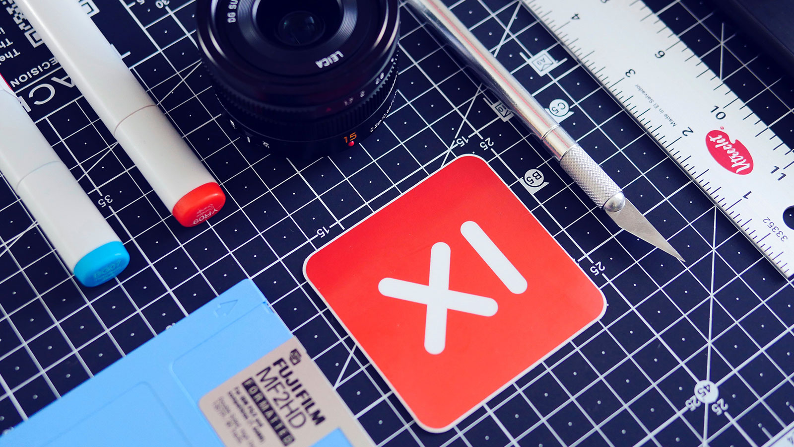 Markers, a ruler, and a camera lens on a desk