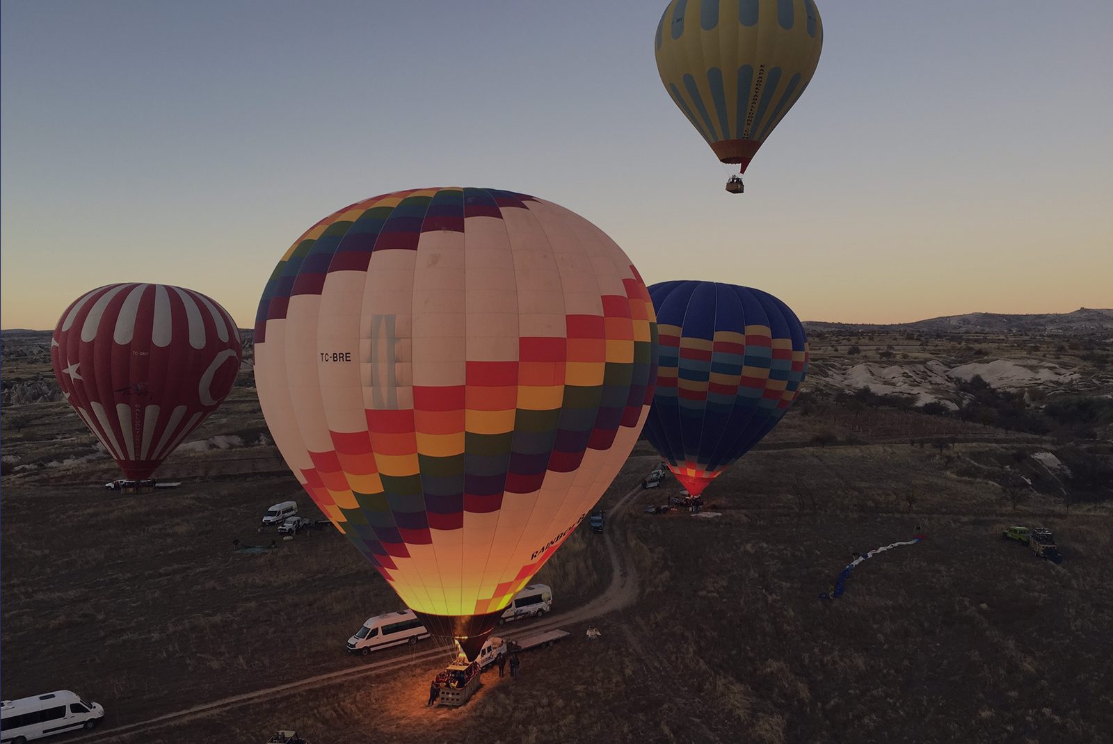 A group of hot air balloons flying over the ground.