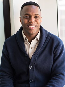A man in a blue jacket smiling for the camera.