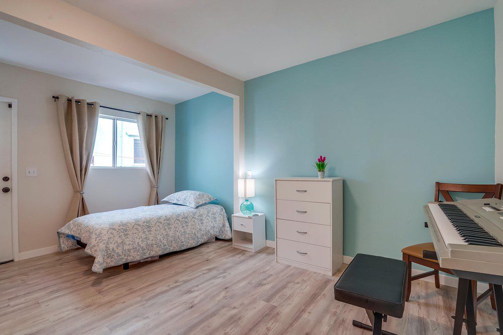 A bedroom with a bed, dresser and window.