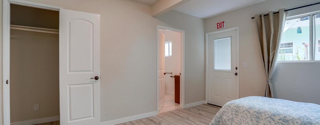 A bedroom with a door open and a window.