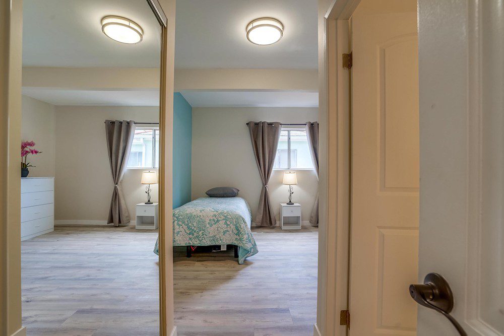 A bedroom with two windows and a bed in it.