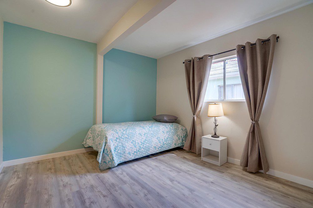 A bedroom with a bed, nightstand and window.