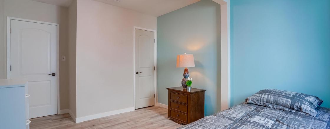 A bedroom with a bed, nightstand and lamp.