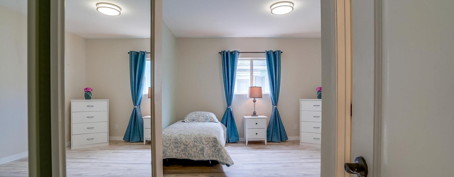 A bedroom with blue curtains and white walls