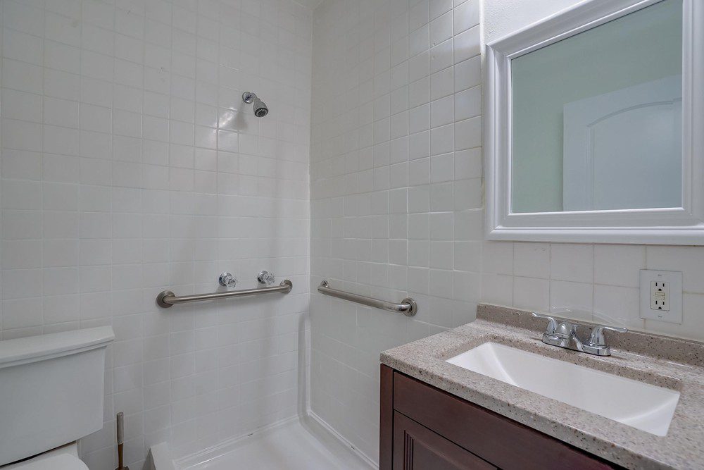 A bathroom with white walls and brown cabinets.