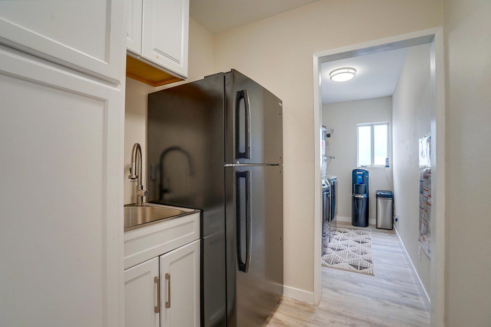 A kitchen with white cabinets and black refrigerator.