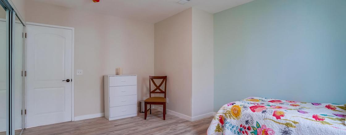 A bedroom with a chair and dresser in it