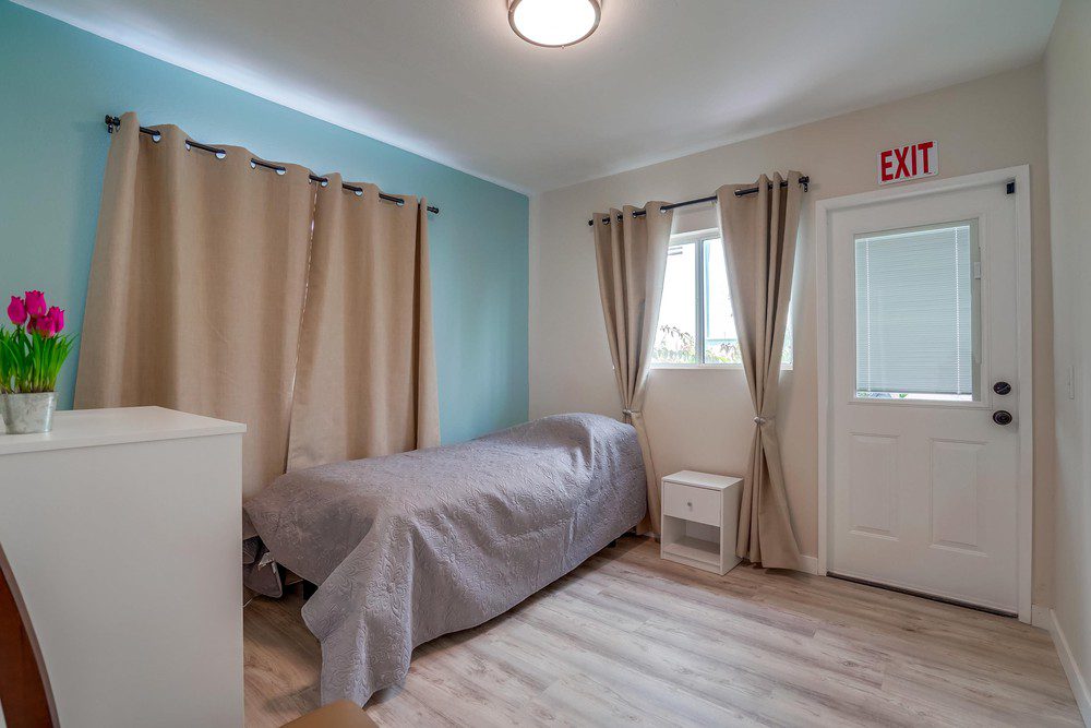 A bedroom with a bed and window curtains.