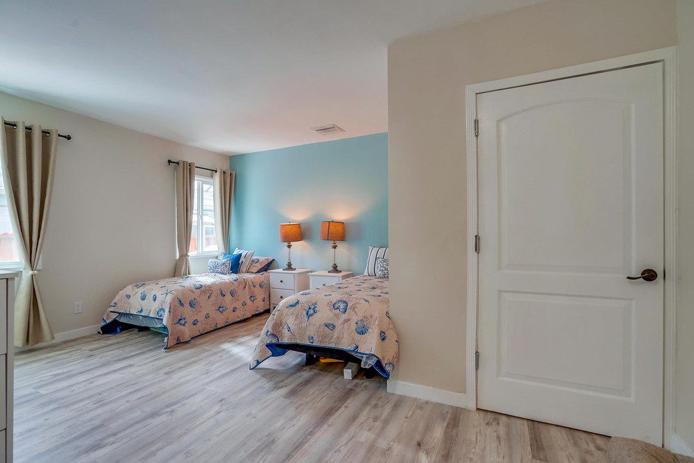 A bedroom with two beds and a door to the bathroom.