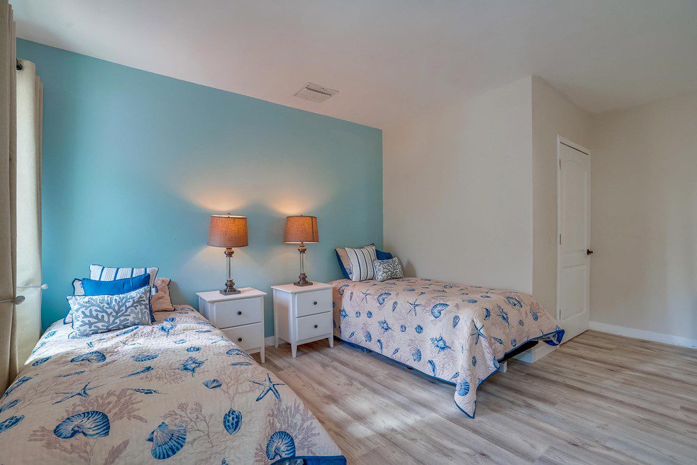 A bedroom with two beds and lamps on the wall.