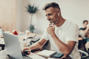 Man working on laptop with earbuds.
