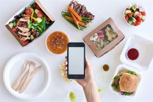 Hand holding a phone among various meals.
